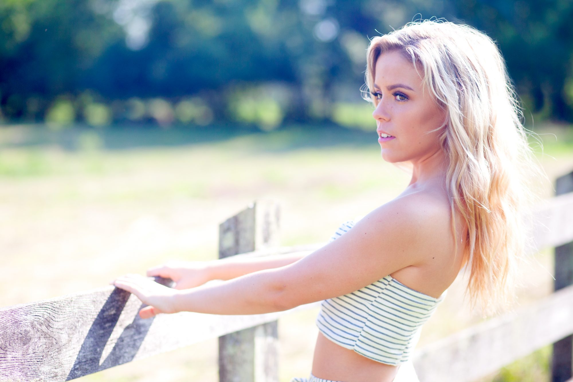 louisville senior girl at blackacre farm holding onto rustic wooden fence.