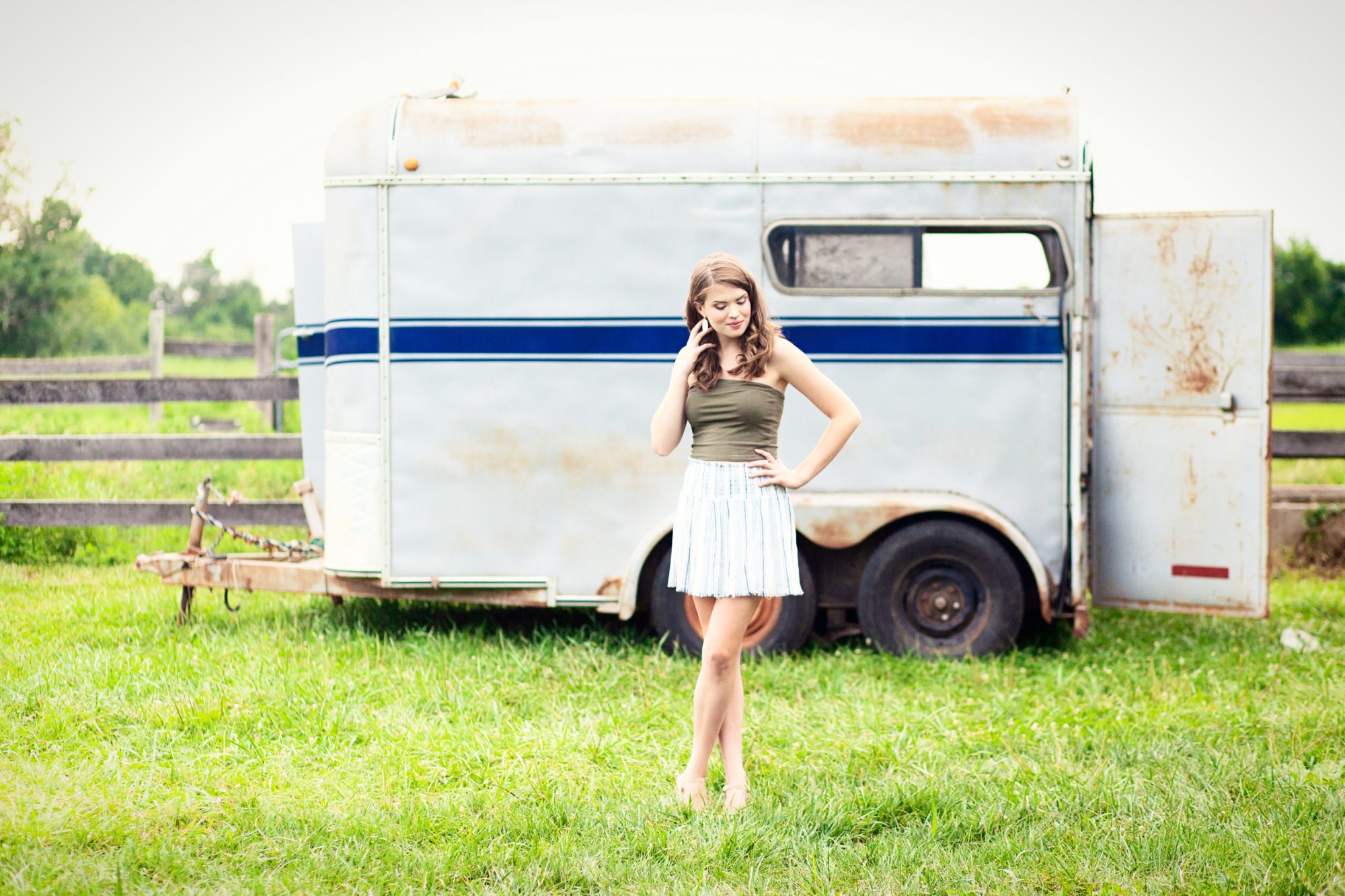 louisville high school senior girl at blackacre farm standing next to blue and white trailor