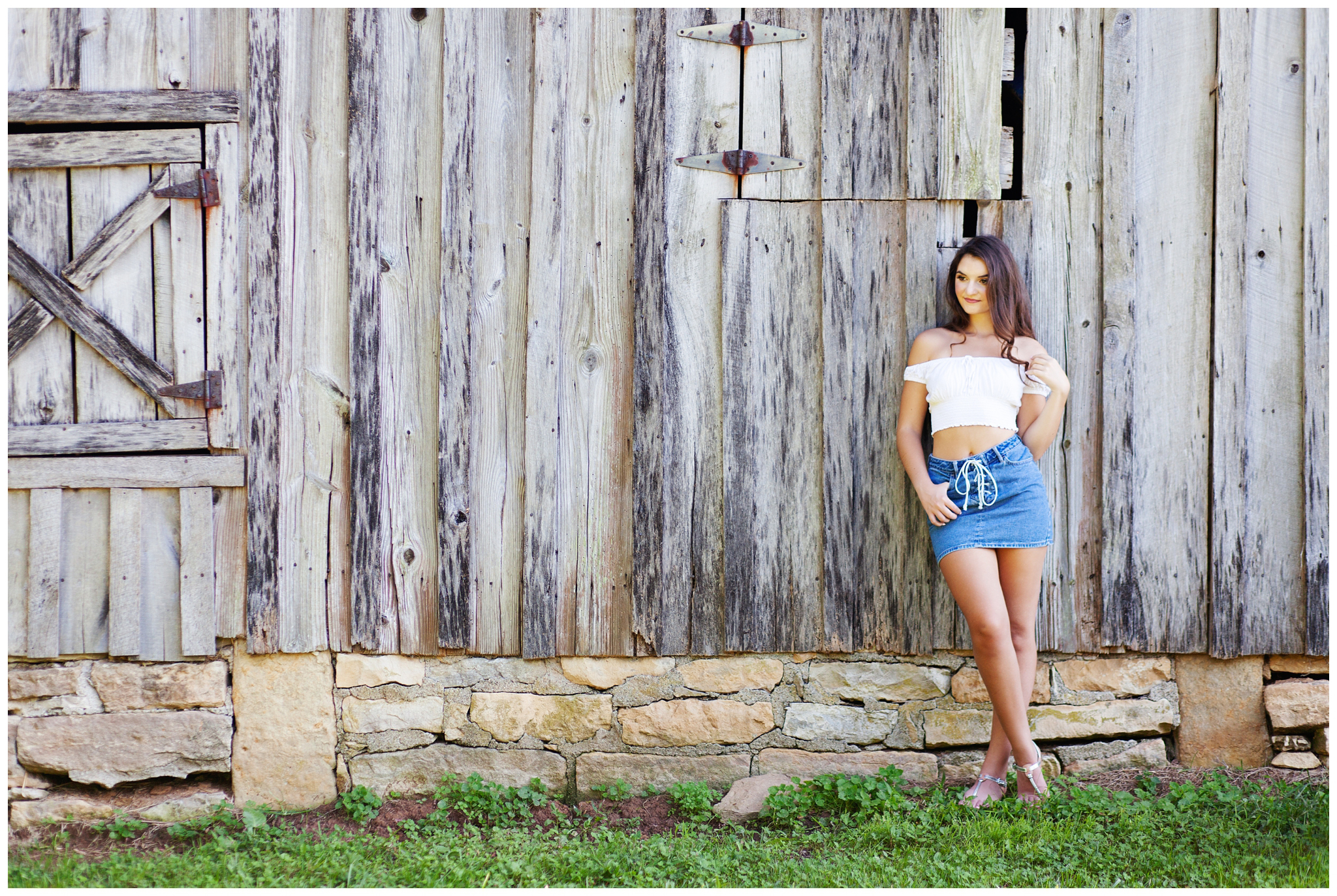 High school senior standing against old wooden barn